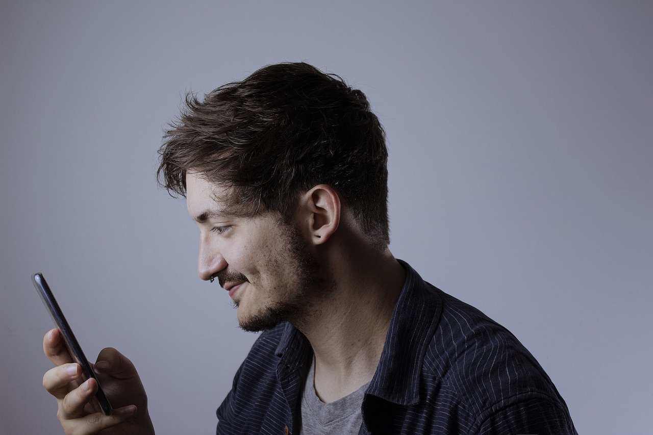 A man smiling as he reads an answer on his phone